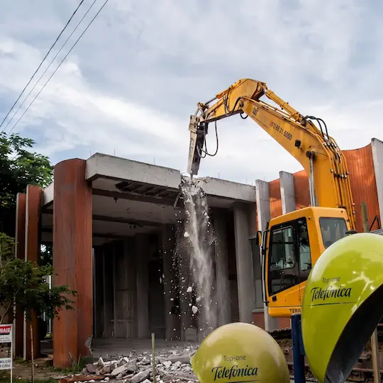 Escavadeira amarela em demolição com maquinário de edificação comercial